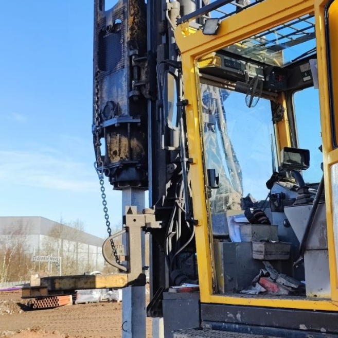 A yellow Aarsleff pile driver being used to install precast concrete piles under a blue sky.