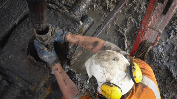 A worker wearing safety gear and a hard hat is engaged in drilling and grouting activities for soil engineering and stabilization using the drilling and grouting technique in civil engineering.