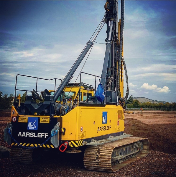 Aarsleff's Yellow Piling Rig Sits On A Dirt Construction Site.