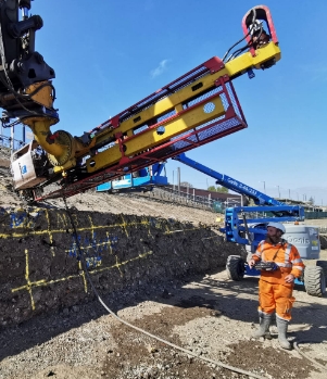 Heavy machinery in operation for a residential project. under a blue sky. A worker in PPE watches nearby.